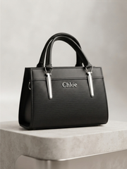 Black textured handbag with silver Chloè logo on a pedestal.