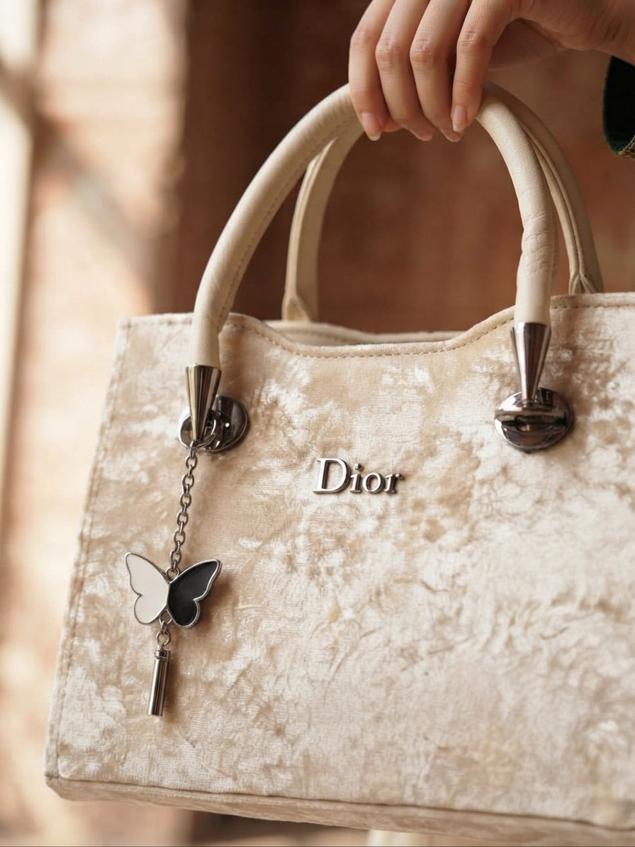 Beige velvet handbag held by a hand, close-up shot.
