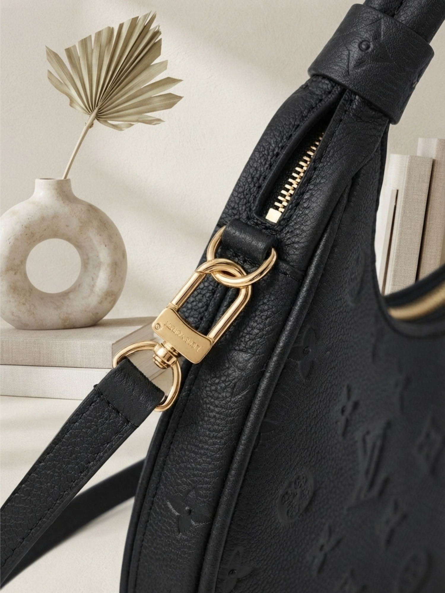 Detailed close-up of the gold-tone hardware and clip on the strap of the black Monogram Empreinte Louis Vuitton Loop bag.