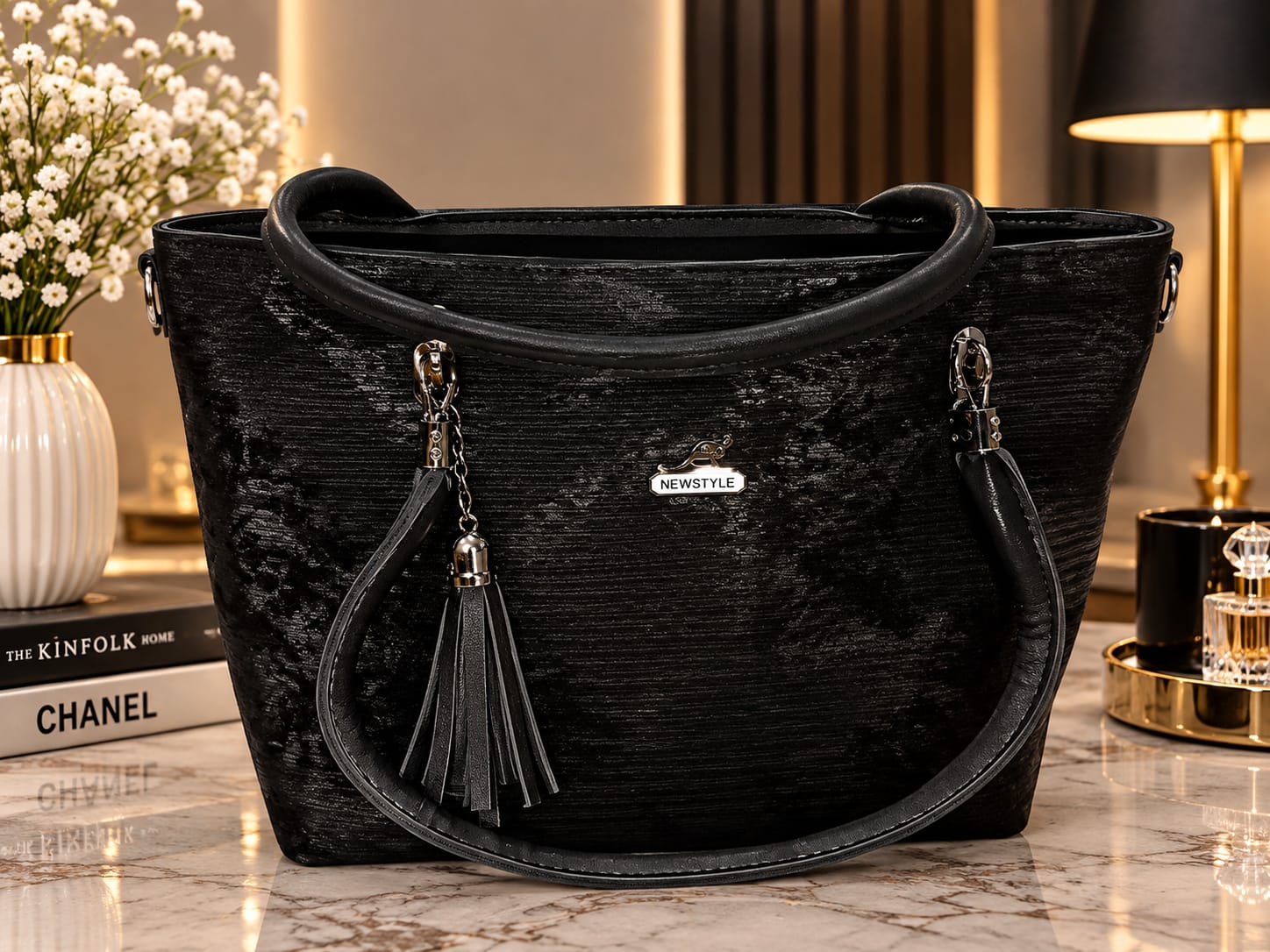 A dark charcoal grey textured tote bag with black handles and a tassel on a marble table.