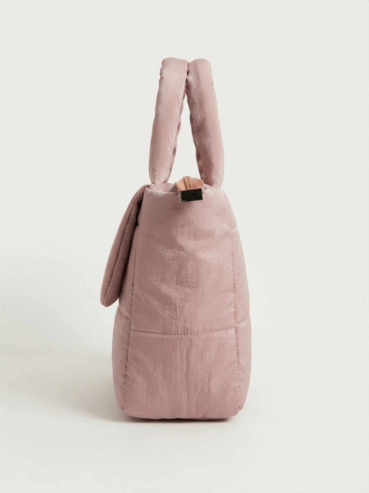 Side profile view of the quilted pink handbag showcasing its depth, structured base, and top handles.