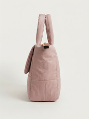Side profile view of the quilted pink handbag showcasing its depth, structured base, and top handles.