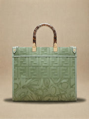 Back view of a sage green Fendi tote bag with an embossed logo pattern and tortoiseshell top handles.
