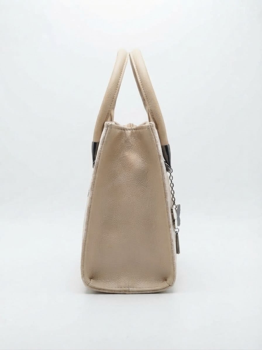 Side view of the beige velvet handbag showing gold leather trim.