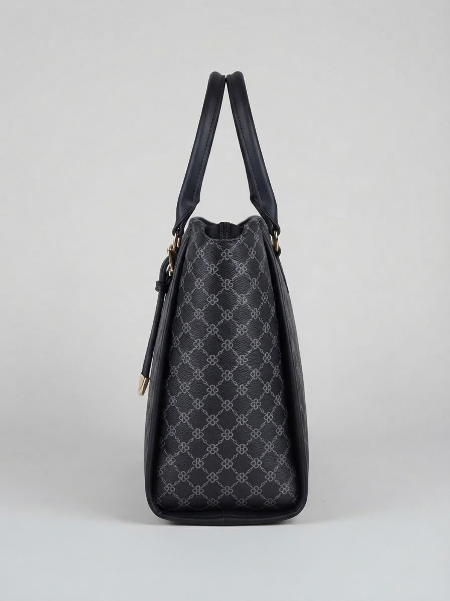 Side profile view of the black printed tote bag highlighting its structured depth and top handle against a neutral backdrop.