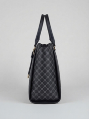 Side profile view of the black printed tote bag highlighting its structured depth and top handle against a neutral backdrop.