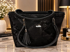 A dark charcoal grey textured tote bag with black handles and a tassel on a marble table.
