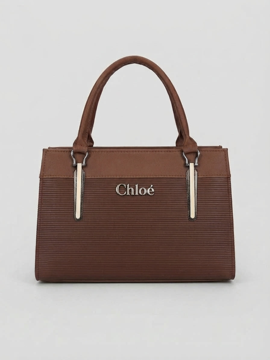 A front view of a brown structured handbag with top handles and vertical silver hardware accents.