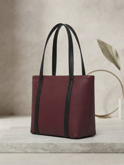 Three-quarter angle of the maroon textured tote bag showcasing its side depth and dual black straps.