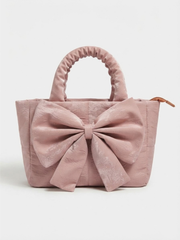 Front view of the pink quilted satchel bag highlighting the large bow accent against a neutral background.
