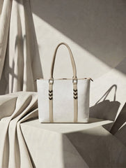 Three-quarter angle of the white textured tote bag showcasing its side depth, dual straps, and elegant neutral backdrop.